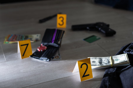 High contrast image of a crime scene with gun and markers on the floorの写真素材