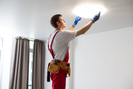 Young man installing ceiling lamp on stepladder in kitchenの写真素材