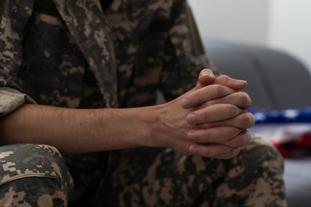 A man in a military uniform is sitting in a chair by the window. Concept: a soldier at a...