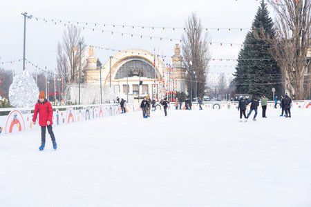 KYIV, UKRAINE - Dec. 23, 2022: Ice-skating people. People have fun in ice arena at the city ice rink. New Years holidays in city Kyiv. Kyiv Christmas and New Year decorations.のeditorial素材