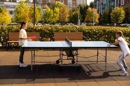 Kid playing table tennis outdoor with family