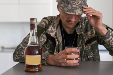 Upset young man drinker alcoholic sitting at bar counter with glass drinking whiskey alone, sad depressed addicted drunk guy having problem suffer from alcohol addiction abuse, alcoholism conceptの写真素材