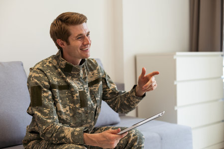Happy young soldier holding a computer tablet