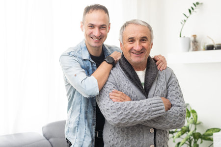 Handsome smiling adult man hugging senior mature father, looking at camera. Happiness, love and...