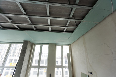 Installation of drywall. Workers are using screws and a screwdriver to attach plasterboard to the ceilingの写真素材