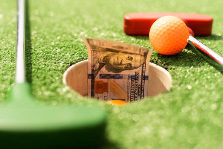 Mini Golf club, ball and money on the artificial grassの写真素材