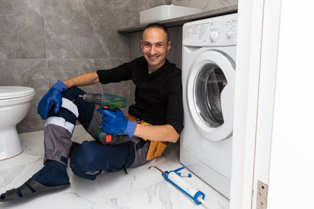 Plumber fixing washing machine on white backgroundの写真素材