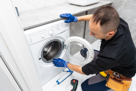Plumber fixing washing machine on white backgroundの写真素材
