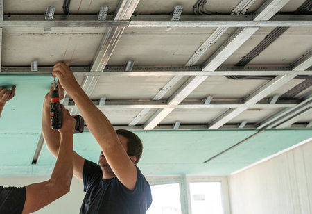 Workers fitting panel into frame of ceiling.の写真素材