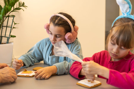 two little sisters decorating homemade cookies in the kitchen at home.