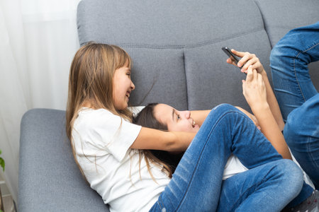people, technology and friendship concept - happy teenage girls taking selfie with smartphone sitting on sofa at homeの写真素材