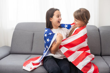 cheerful adorable kids standing under american flag and looking at cameraの写真素材