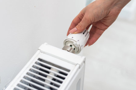Heat radiator knob. Woman hand adjusting temperature on heating radiator