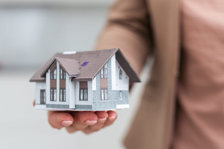 holding house representing home ownership and the Real Estate business