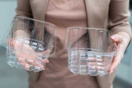 Close up hand holding empty plastic containers on white background. hand throwing empty plastic in...