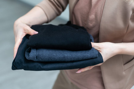 Woman packs clothes for a clothes donation in a box or tidies up