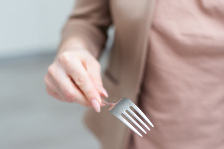 Fork in a hand on a white background isolationの写真素材