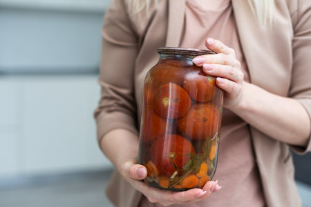 hands tomatoes in a jar on a white background isolationの写真素材