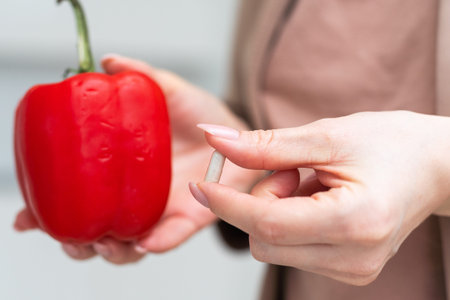 Hand holding red pepper and a pill isolated on white