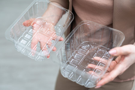 Close up hand holding empty plastic containers on white background. hand throwing empty plastic in...