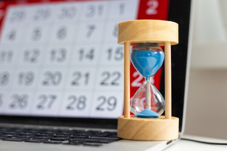 Time passing concept, time slipping away. Hourglass and the calendarの写真素材