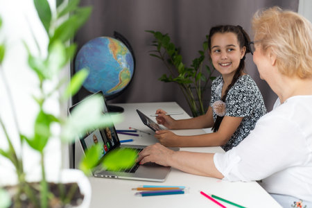 Cute little girl with her grandmother looking at tablet at home