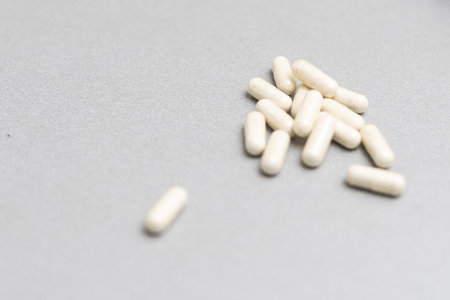 Large number of white pills scattered on a gray surface. Minimal medical, pharmaceutical concept...