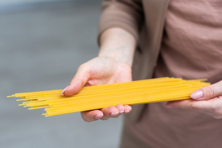 Close up Human Hand Holding Fresh Spaghetti Pasta Italian Dish For Cooking isolated on white background.の写真素材