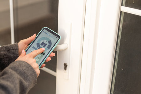 Smiling woman setting home security system with help of mobile application.