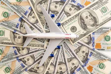 Model passenger aircraft on a background of dollar bills
