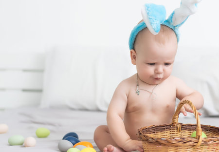 Mother and child with colorful eggs. Mom and baby with bunny ears. Parent and kid play indoors in...