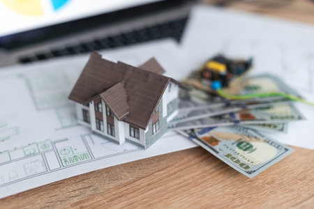 Model house on top of money pile suggesting savings for a house
