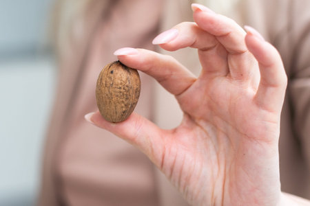 Woman hand holding walnuts, isolated on white, studio shot.