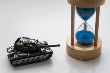 The plastic tank toys on the floor next to an hourglass