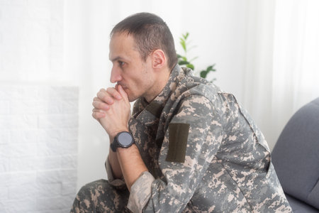 Portrait of calm serious Caucasian military man wearing camouflage uniform and cap sitting on a...