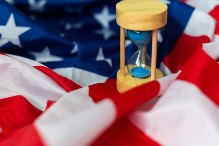 Hourglass and USA flag, soft focus, copy space