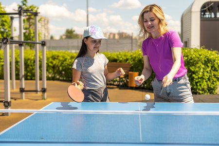 Young woman with her daughter playing ping pong in park