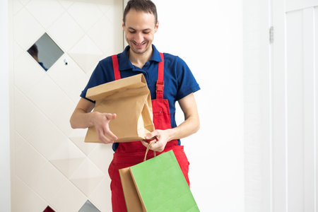 Two boxes with fast food being carried by delivery man in uniform for one of clients