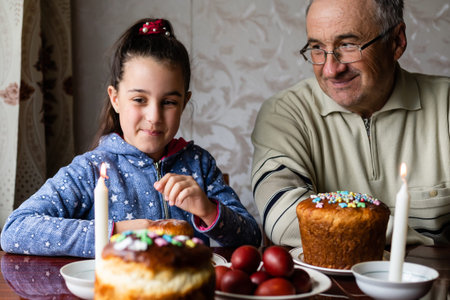 grandfather and granddaughter at a festive table to celebrate Easterの写真素材