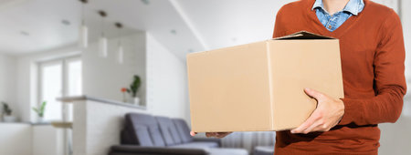 young man carries moving boxes