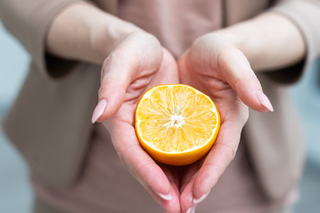 A female hand holding an orange slice, over white background with using pathの写真素材