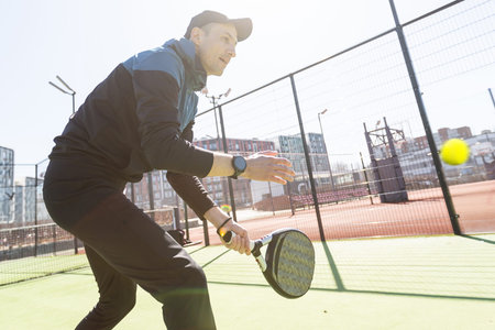 Man playing padel in a green grass padel court indoor behind the net