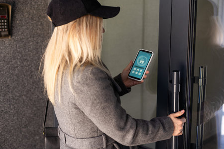 Woman locking smartlock on the entrance door using a smart phone. Concept of using smart electronic...