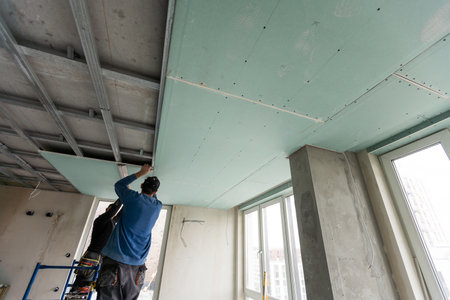 Workers fitting panel into frame of ceiling.の写真素材
