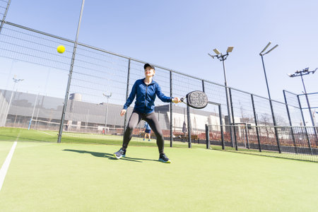 woman playing paddle tennis outdoors.の写真素材