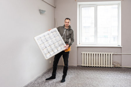 Maintenance man changing light bulbs in officeの写真素材