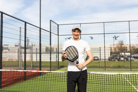 Young man playing paddle tennis on a green court, wearing a t-shirt.Sports concept.Copy spaceの写真素材