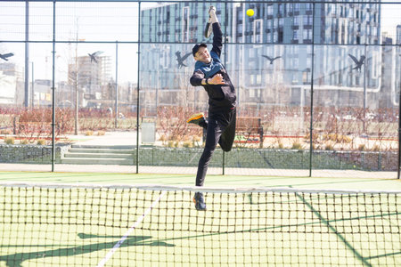 A padel player jump to the ball, good looking for posts and poster. Man with black racket playing a...