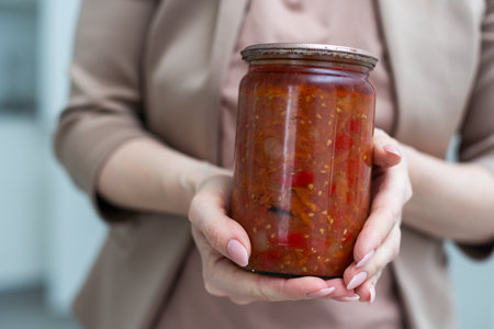 vegetable lecho in a glass jar on a white backgroundの写真素材