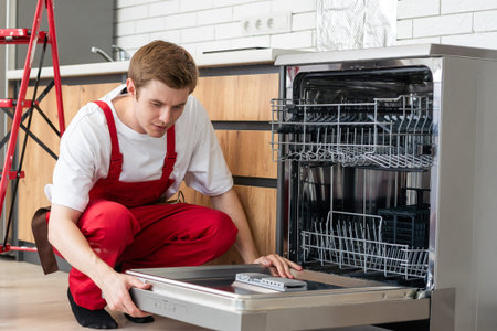 Repair of dishwashers. Repairman repairing dishwasher in kitchenの写真素材